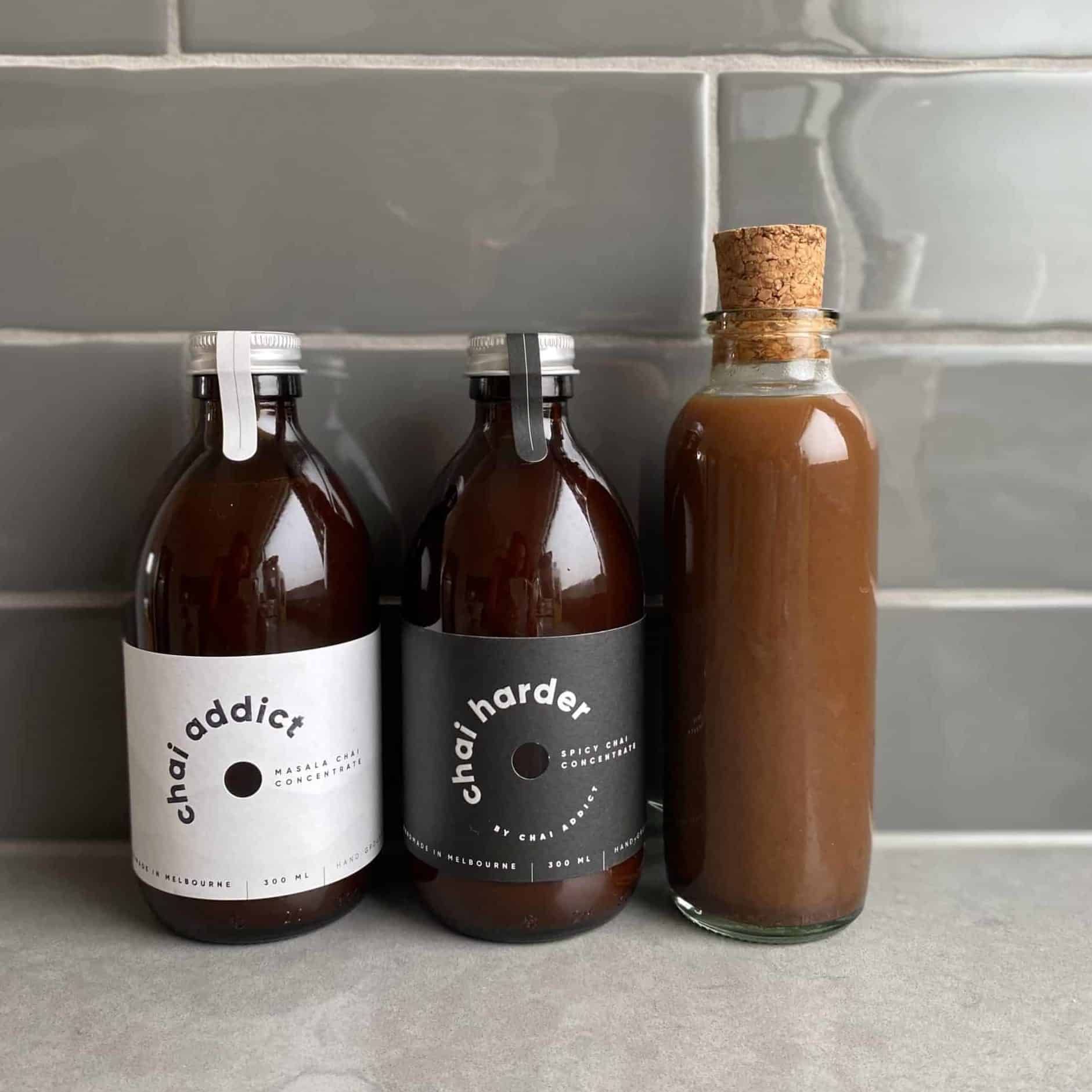 three bottles of chai concentrates, the third a clear bottle of reduced chai concentrate