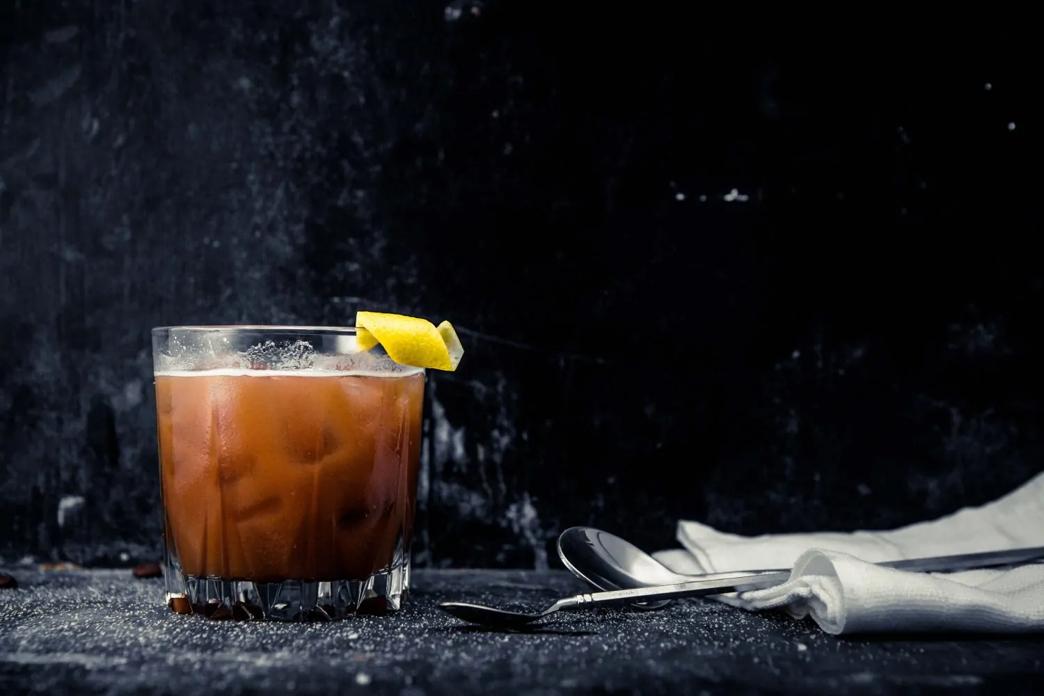 a ball glass of Nighty Night Chai Old Fashioned with a lemon twist