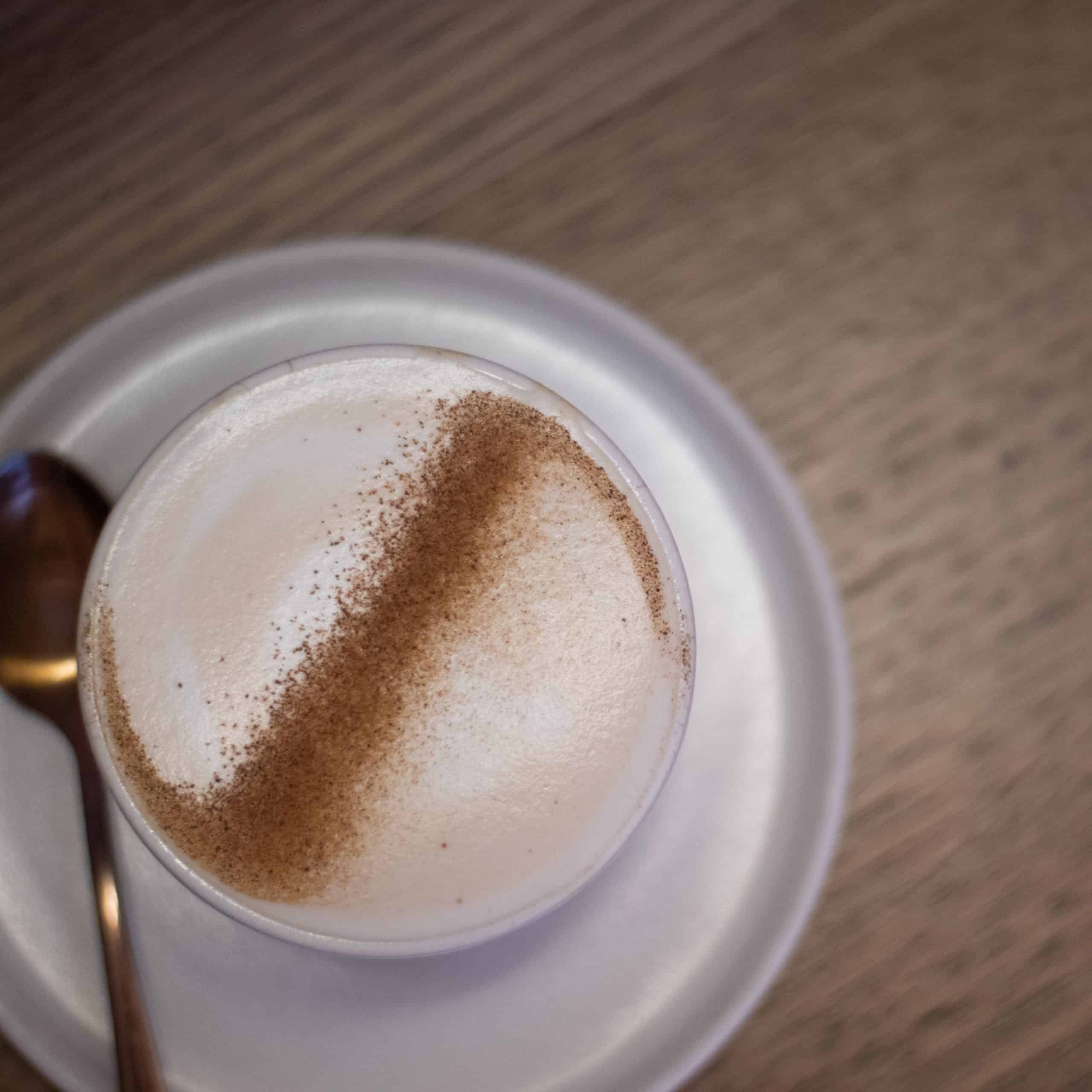beautiful cup of chai addict chai latte served on a ceramic saucer