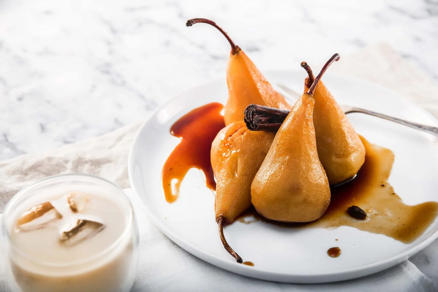 chai harder spice poached pears on a plate served with iced chai latte