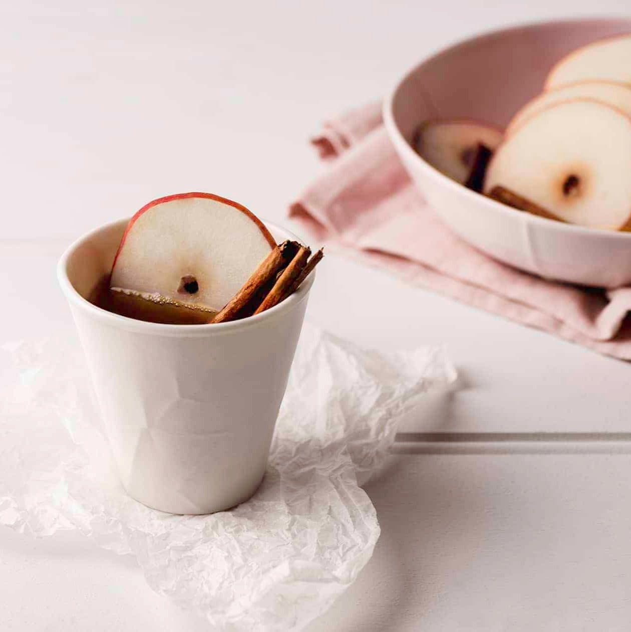 enticing cup of hot chai tea served with round slice of apple and cinnamon in a white ceramic cup
