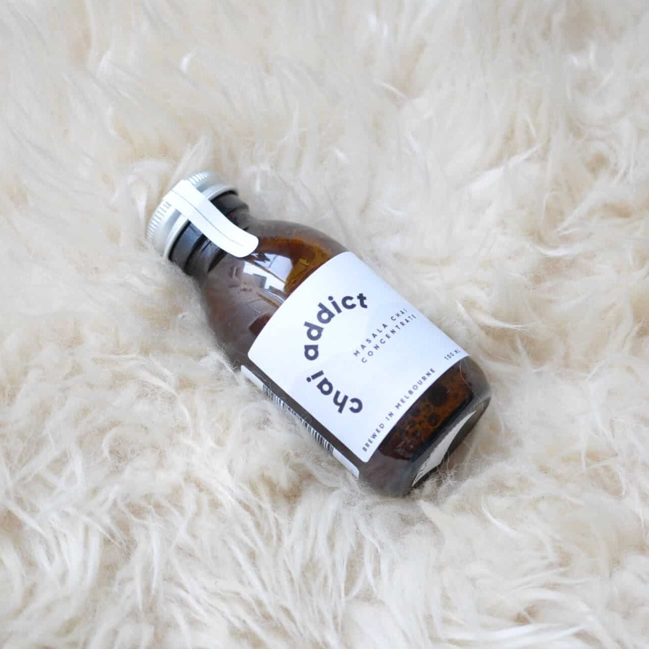 100ml chai addict logo on top of a warm and comforting shaggy white rug with a book