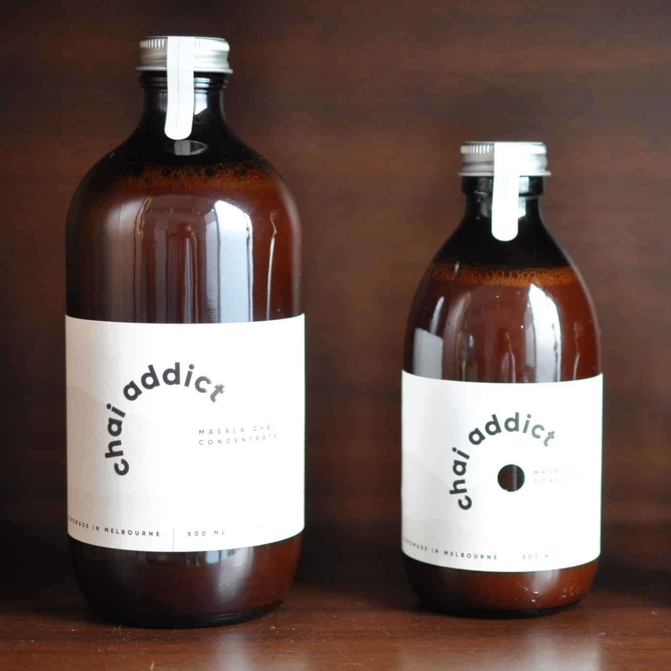 300ml and 500ml bottles of chai addict masala chai concentrates against a brown mid-centrury buffet