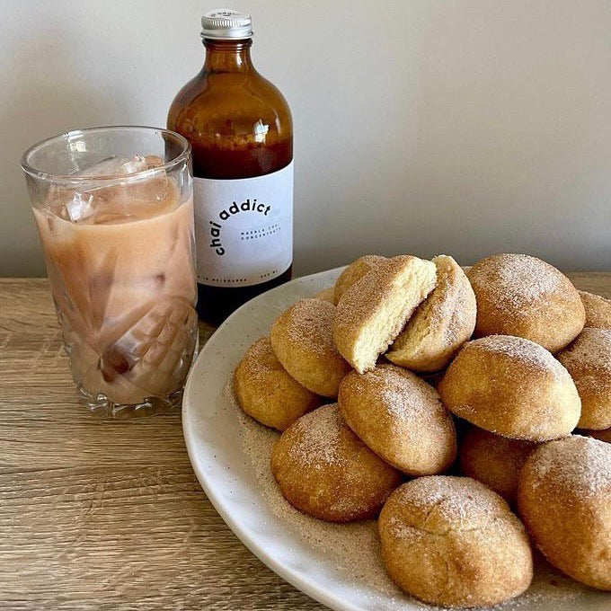 a pile of freshly baked, soft and fluffy chai flavoured snickerdoodles served with a side of iced chai latte