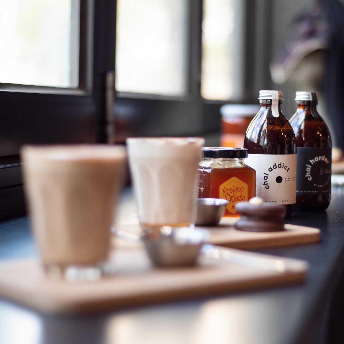 Cups of chai latte brewed served at a cafe accompanying delicious treats, honey and chai latte concentrates