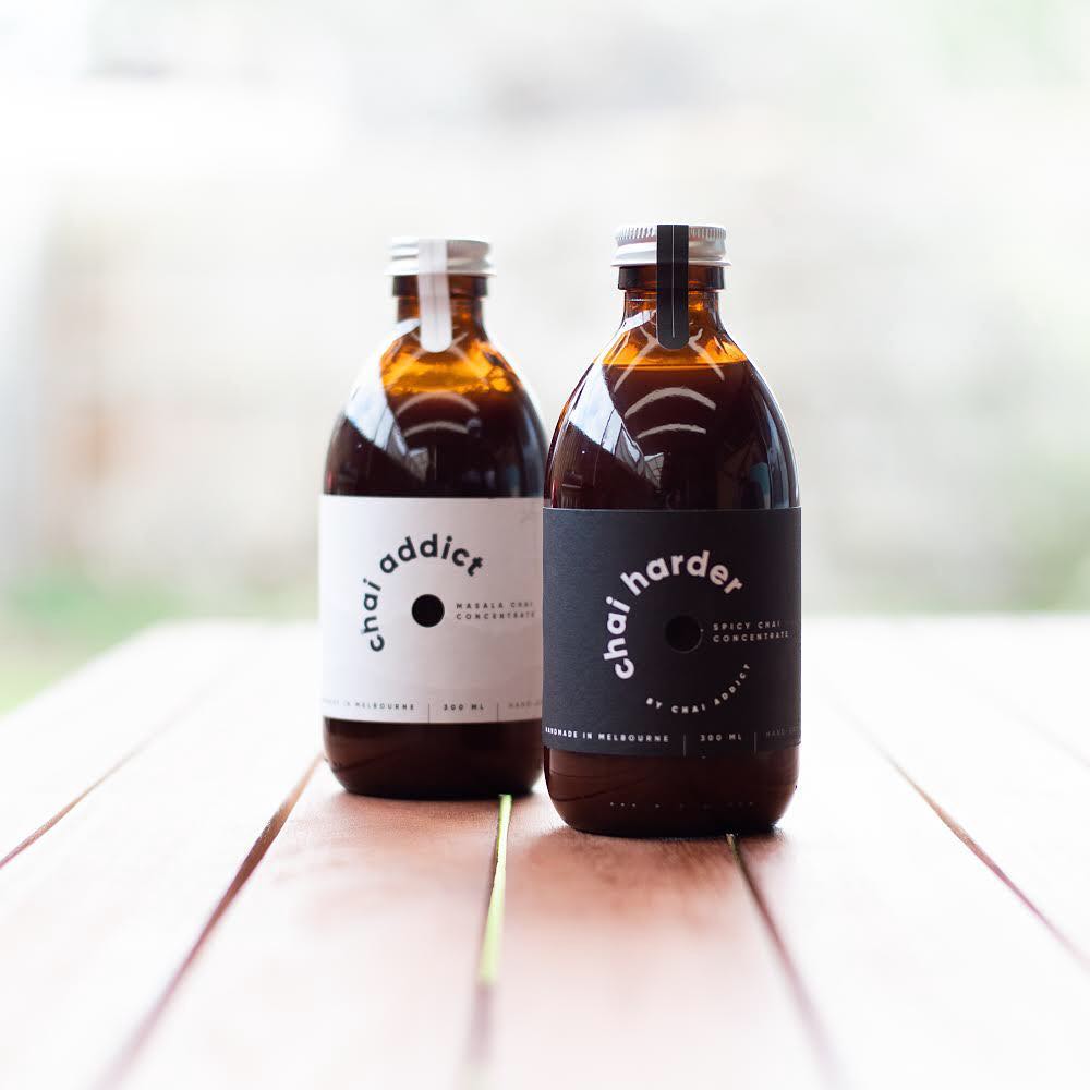 two 300ml brown bottles of chai concentrates by chai addict on a wooden table