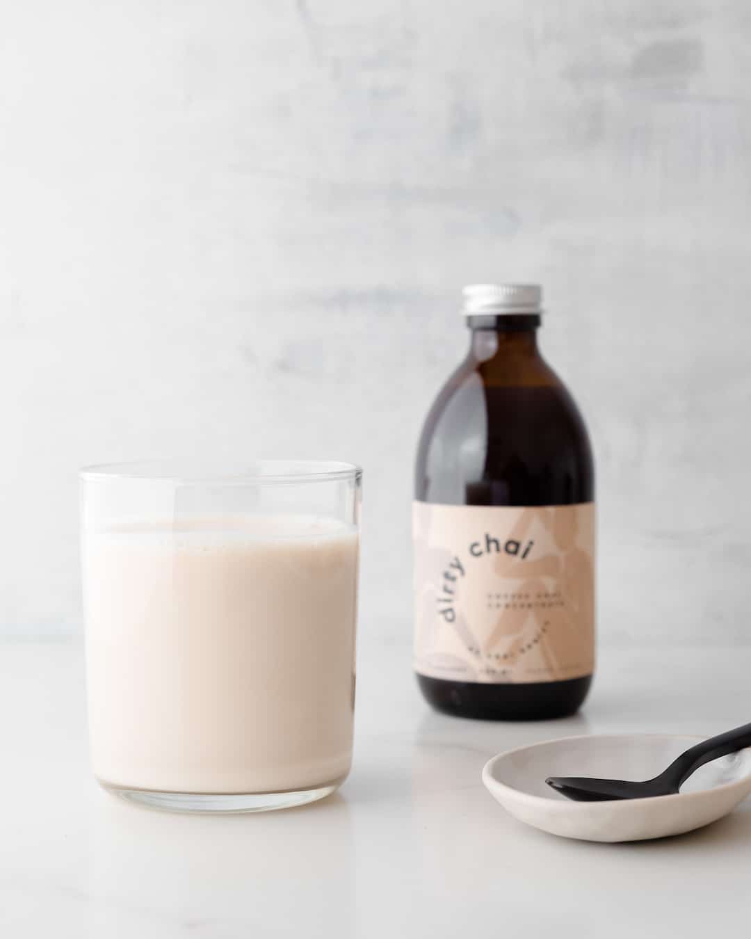 iced dirty chai in a glass with 300ml dirty chai concentrate in the background