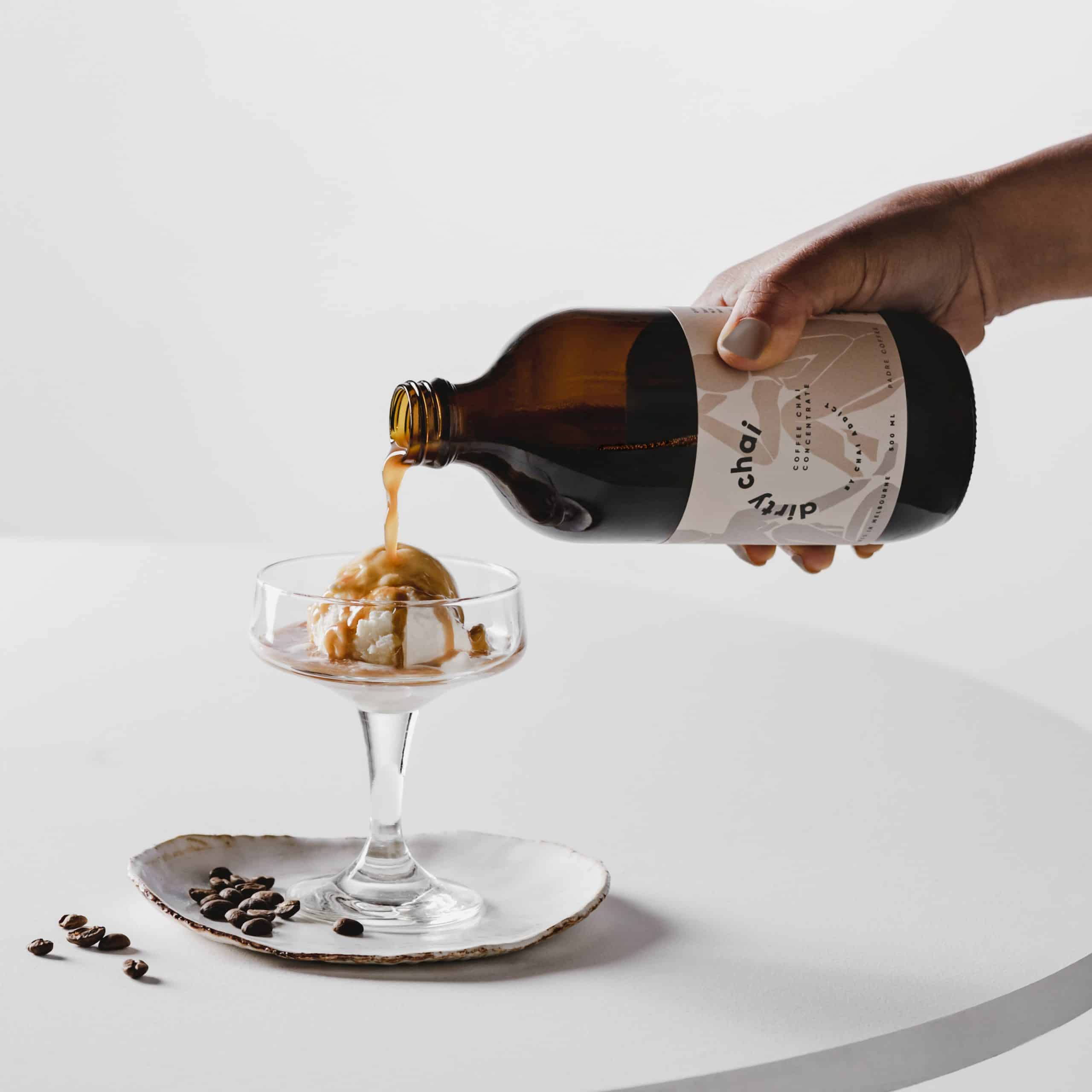 dirty chai concentrate being poured over ice cream in a fancy glass to make an affogato dessert