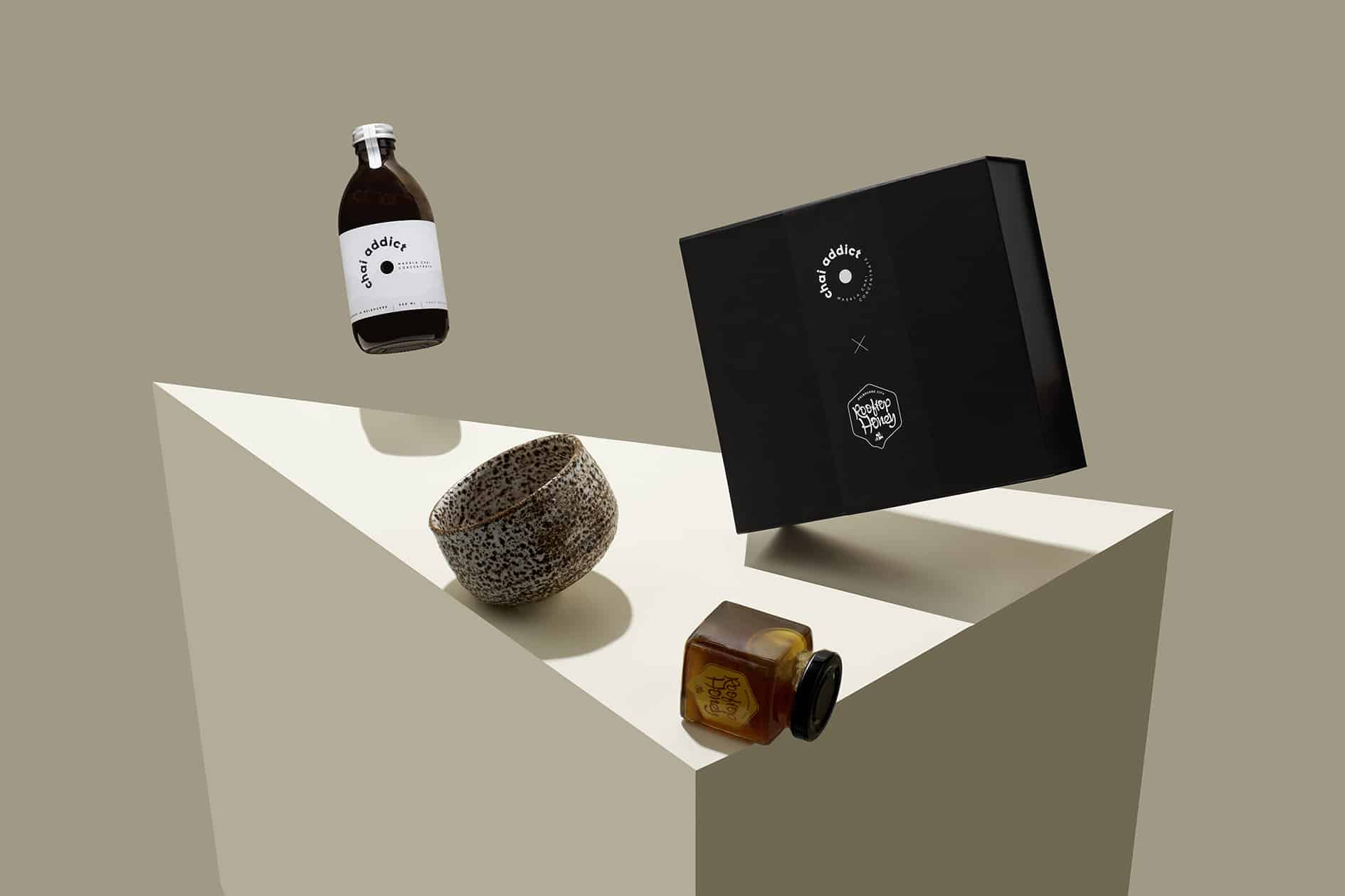 300ml chai addict levitating next to tilted black box, ceramic spotted brown cup and jar of honey