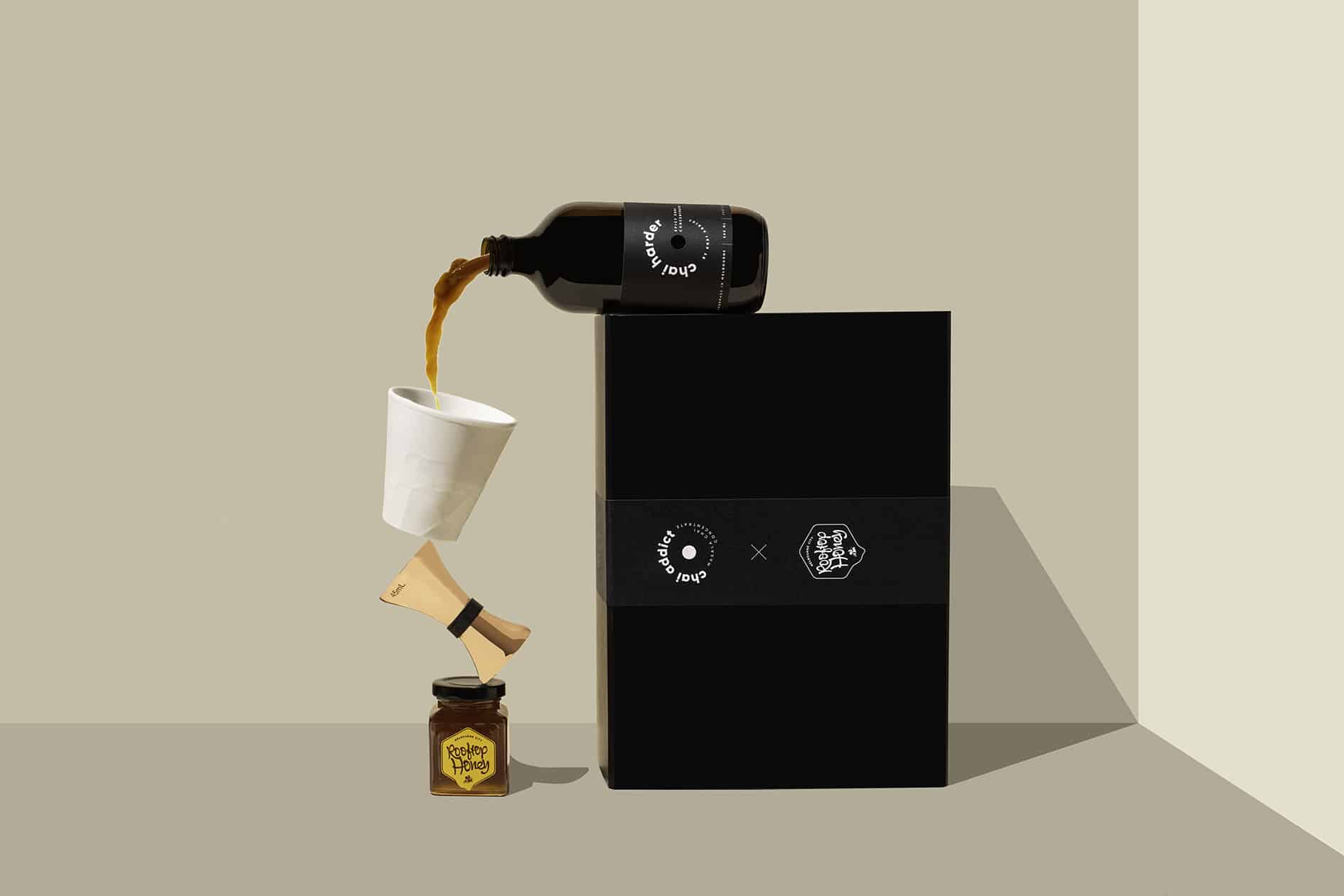 chai harder spicy chai concentrate on chai addict gift box spilling liquid in white ceramic cup balancing on a jigger and jar of honey