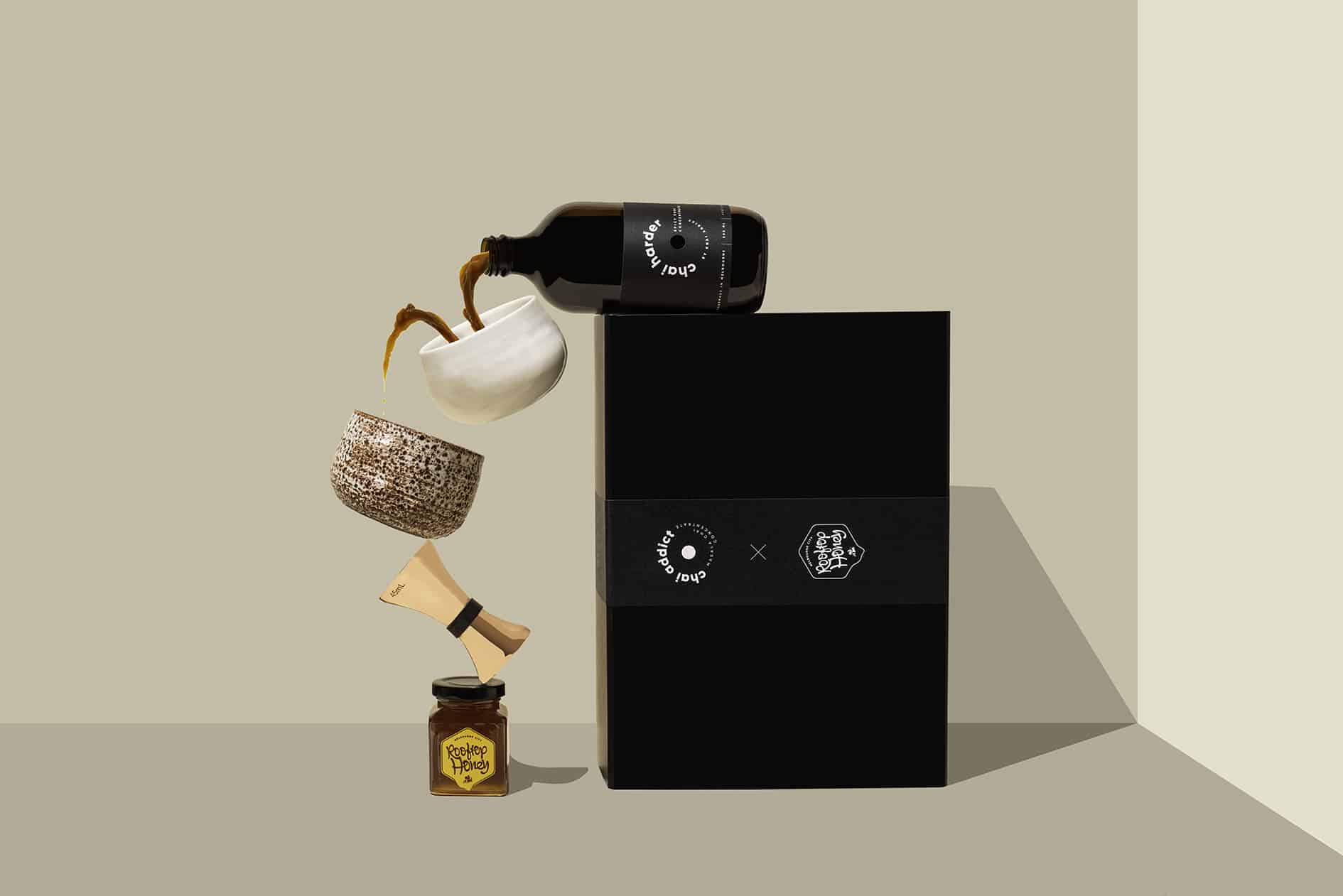 chai harder spicy chai concentrate on chai addict gift box spilling liquid in white ceramic cup balancing on a jigger and jar of honey
