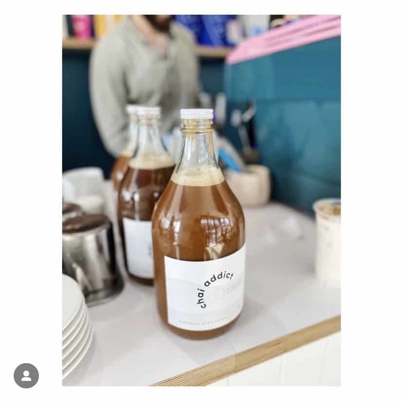 two litre bottle of chai addict chai latte concentrate sitting on a cafe bench