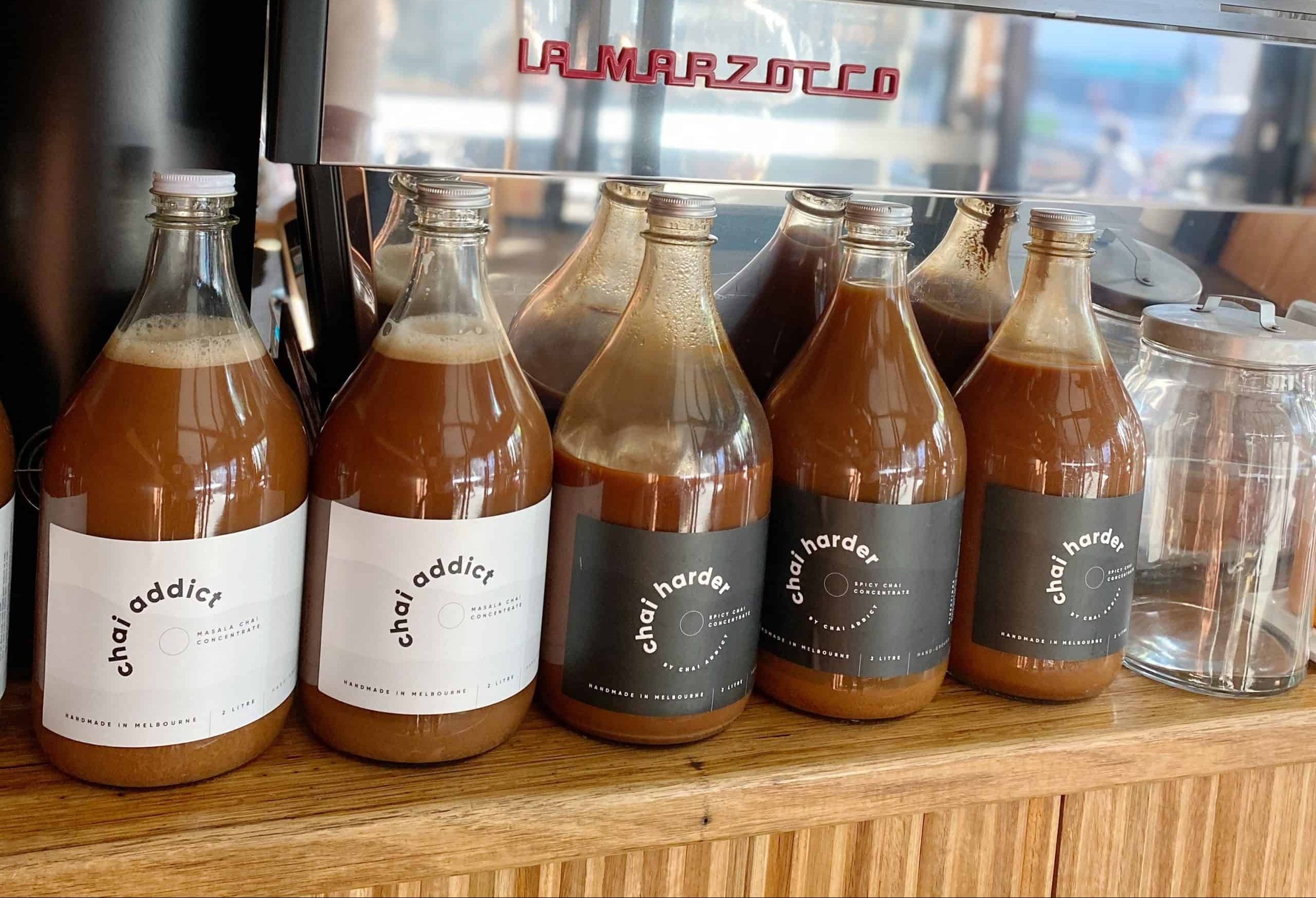 foodservice chai addict bottles displayed on a cafe bench