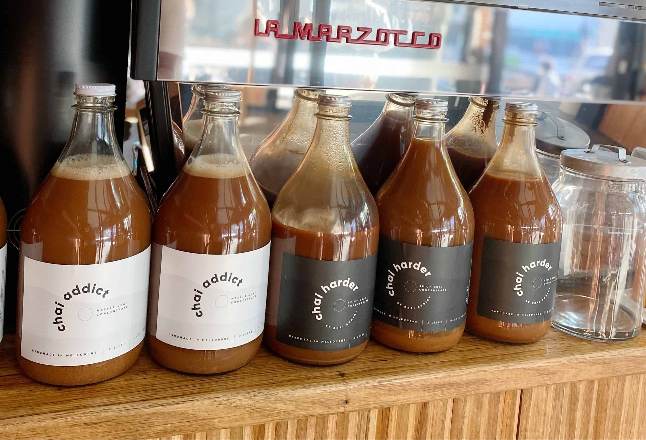 foodservice chai addict bottles displayed on a cafe bench 