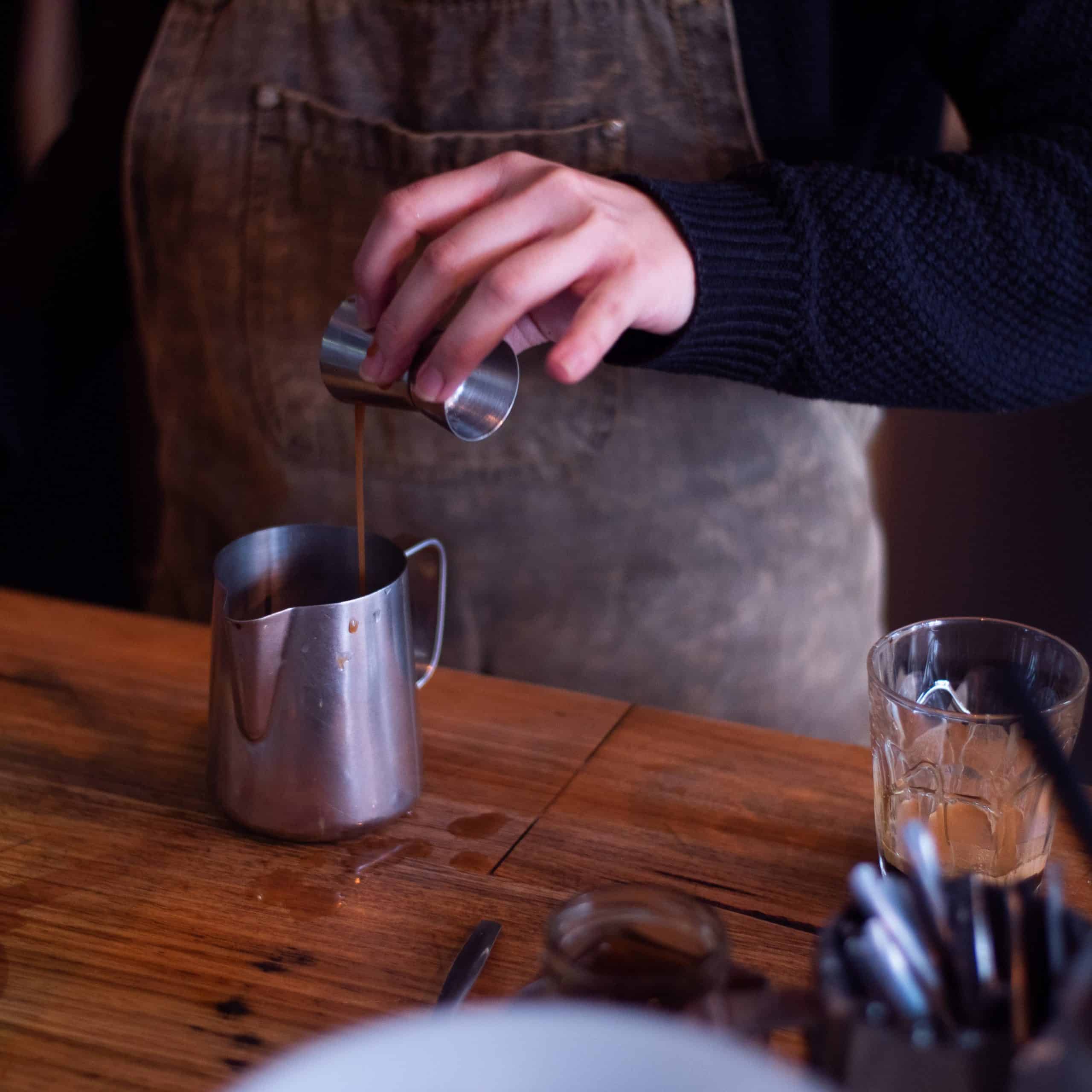 barista pouring chai concentrate to a milk jug
