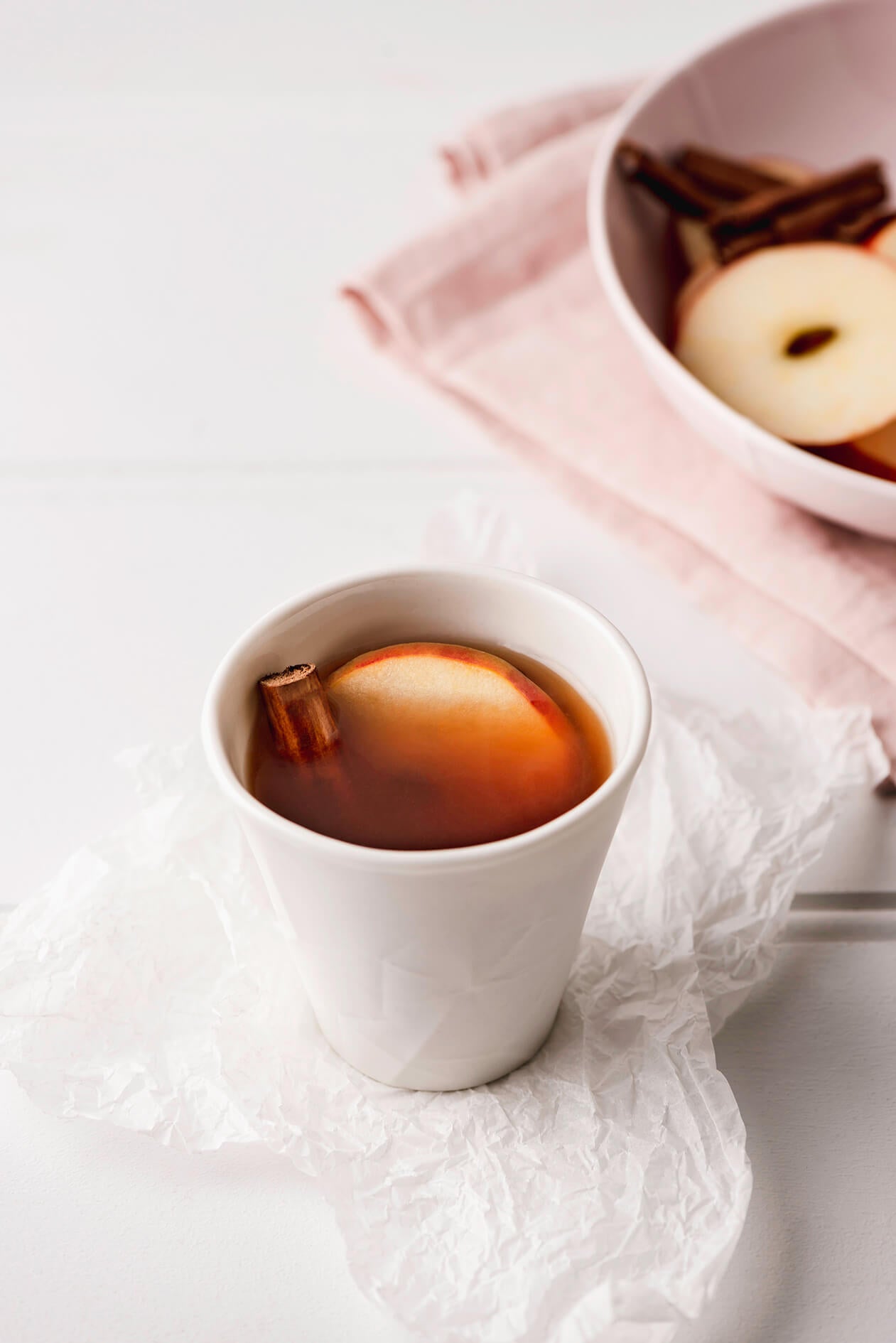 black chai tea with a slice of apply and cinnamon stick