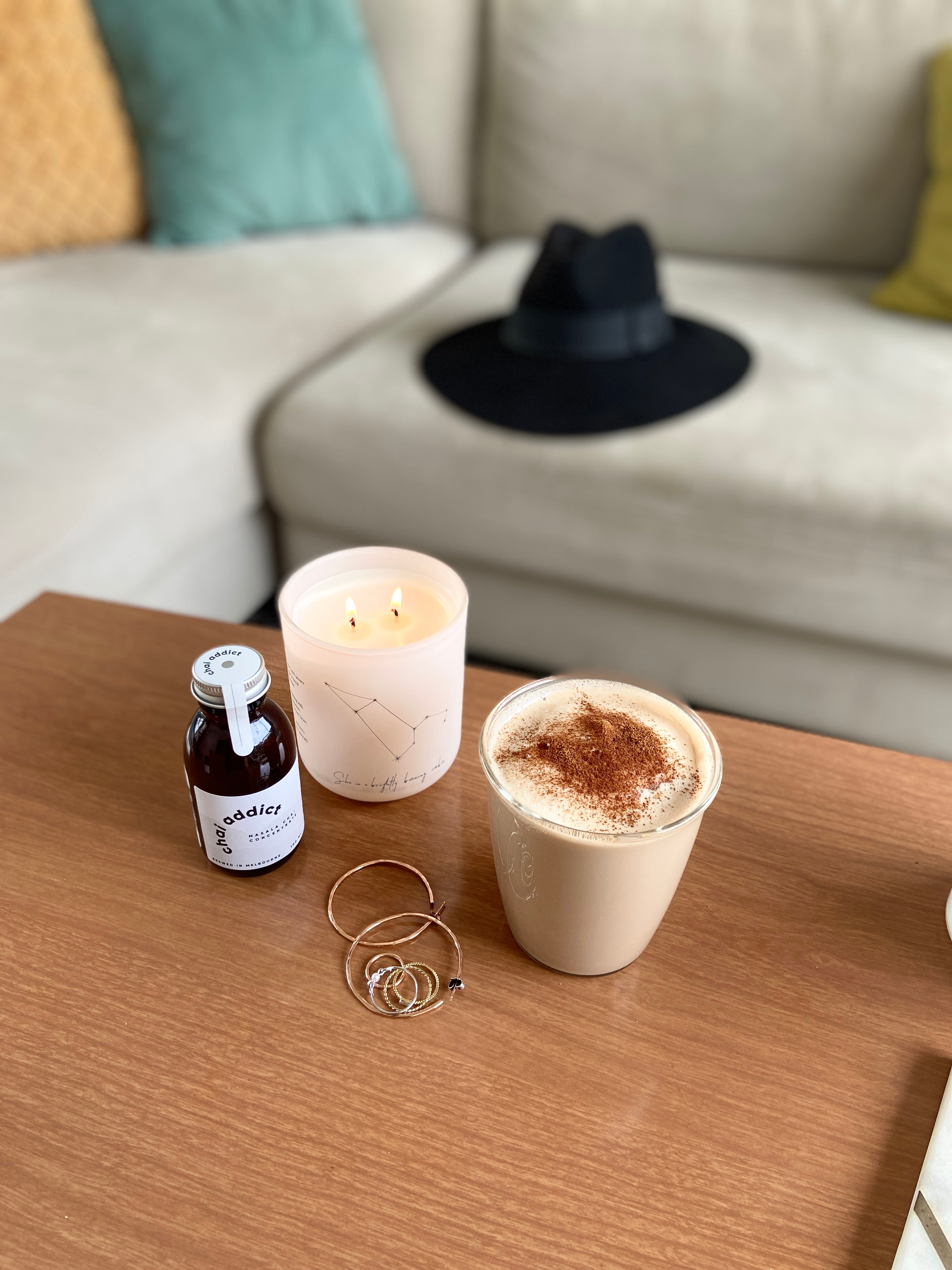 chai latte on table with candle and jewellery